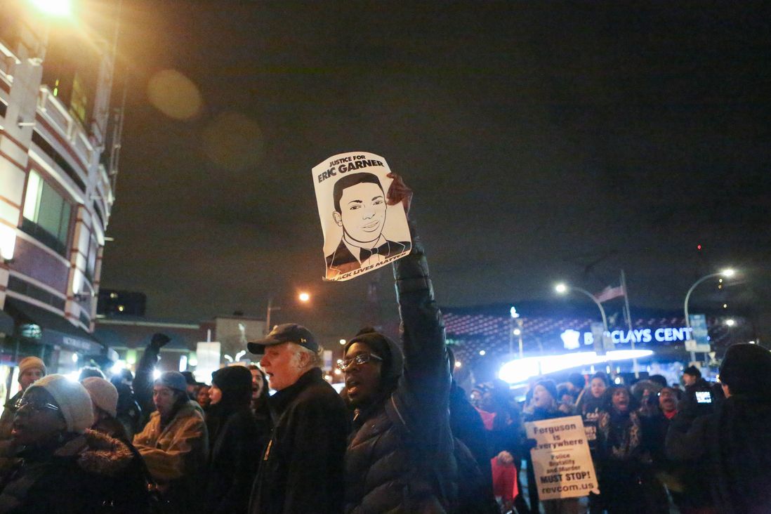A demonstrator holds a sign with a drawing of Eric Garner outside the Barclays Center.<br>